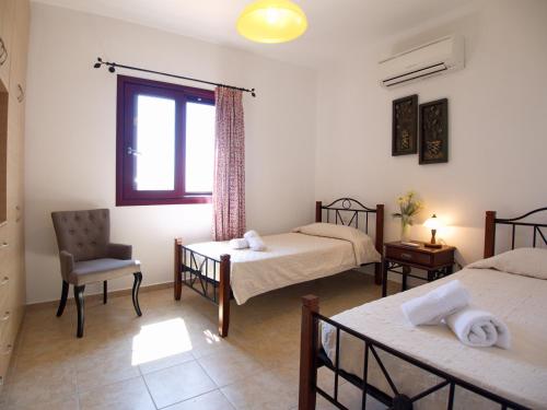 a room with two beds and a chair and a window at Villa Estia Spartia Kefalonia in Kefallonia