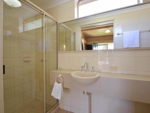 a bathroom with a sink and a shower with a mirror at The Tower Hotel in Kalgoorlie