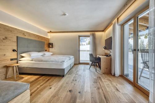 a bedroom with a bed and a desk and window at Brunelle Seiser Alm Lodge in Alpe di Siusi
