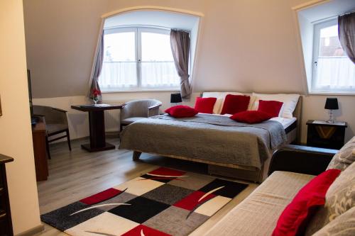 a bedroom with a bed with red pillows and a window at Vadász Panzió és Étterem in Szombathely