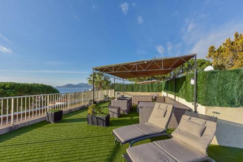 um pátio com espreguiçadeiras e uma cerca em SERRENDY ROOFTOP TERRACE in residential property WITH POOL & SEA VIEW ! em Cannes