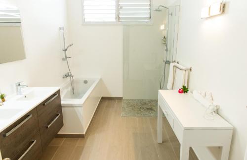 ein Bad mit einer Badewanne, einem Waschbecken und einer Dusche in der Unterkunft Hôtel Frégate Bleue in Le François