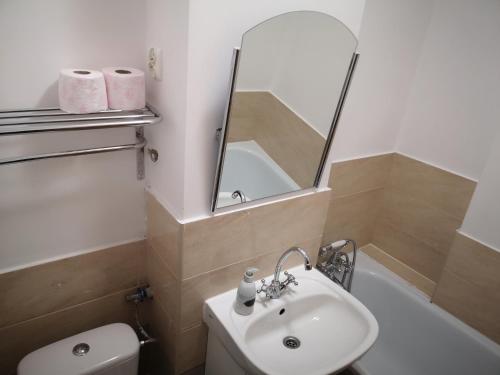 Un baño con lavabo, inodoro y espejo. en Hard Center, en Varsovia