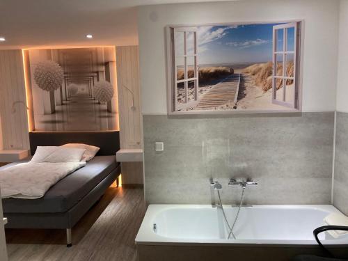 a bedroom with a bed and a bath tub with a picture of a beach at Messe-Hotelzimmer-Einzimmerappartement in Leverkusen