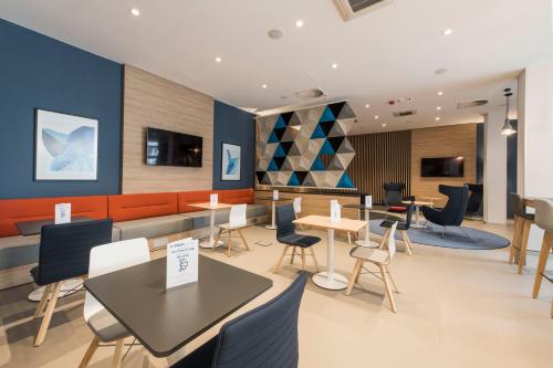 a restaurant with tables and chairs in a building at Holiday Inn Express Warsaw - Mokotow by IHG in Warsaw