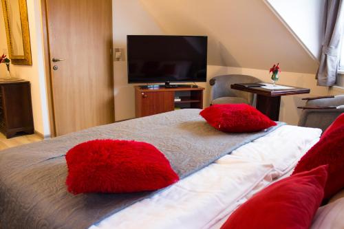 a bedroom with a bed with red pillows on it at Vadász Panzió és Étterem in Szombathely