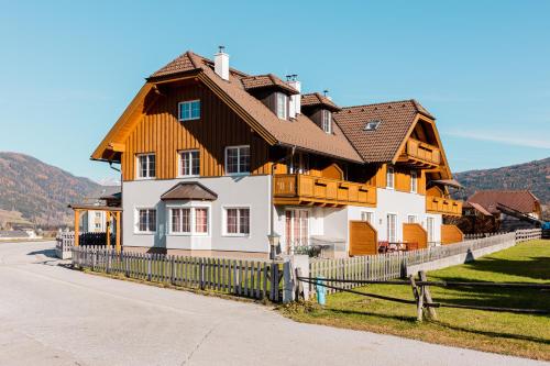 a large wooden house with a fence next to a road at Penthouse Aineckblick in Sankt Margarethen im Lungau