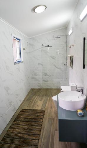a white bathroom with a sink and a shower at Casa Três Picos in Horta