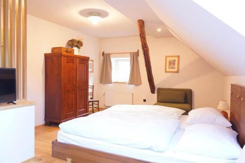 a bedroom with a white bed and a tv at Tourist Farm Zelinc in Cerkno