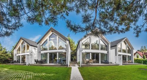 ein Haus mit großen Fenstern auf einem Rasen in der Unterkunft Housea Domy Wakacyjne in Jantar