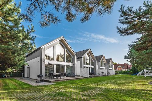 ein Haus mit großen Fenstern und einem Rasen in der Unterkunft Housea Domy Wakacyjne in Jantar
