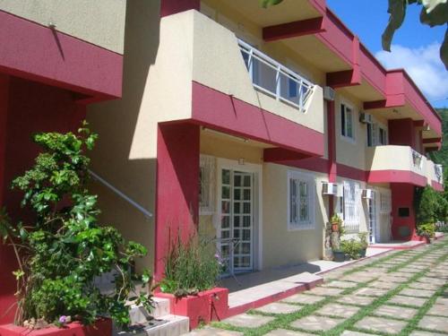 a red and white building with a pathway in front of it at Departamentos Vale Encantado in Bombinhas