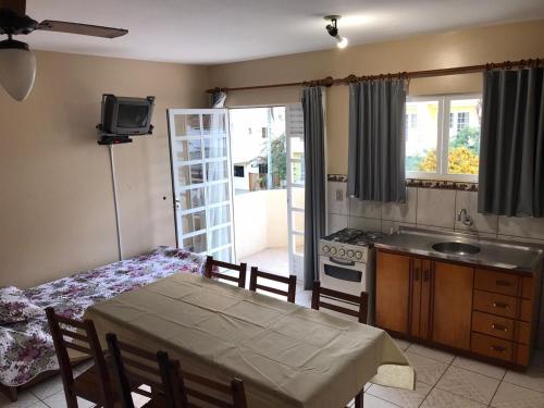 a kitchen with a table and a kitchen with a sink and a stove at Departamentos Vale Encantado in Bombinhas