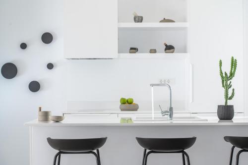 a kitchen with a white counter and four stools at Cocoon Luxury Villas in Hersonissos