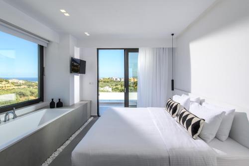 a white bedroom with a large bed and a large window at Cocoon Luxury Villas in Hersonissos