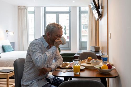 un uomo seduto a un tavolo con un piatto di cibo di Feel Porto Corporate Housing Marquês a Porto