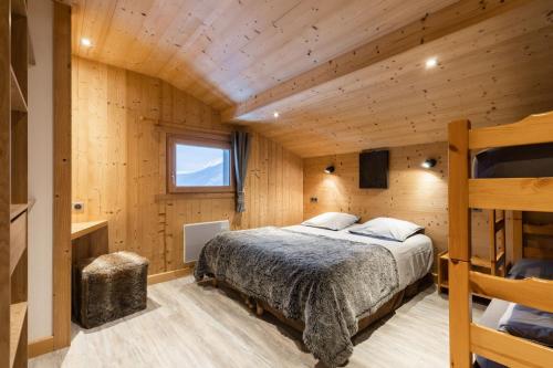 ein Schlafzimmer mit einem Bett in einer Holzhütte in der Unterkunft Chalet Socali Le Grand Bornand in Le Grand-Bornand