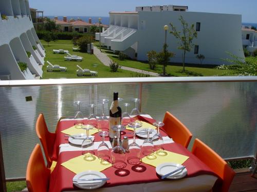 a red table with a bottle of wine on a balcony at Quinta Das Figueirinhas & Quintinha Village in Armação de Pêra