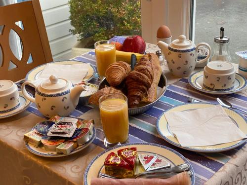 a table topped with plates of food and cups of coffee at Contact hôtel - Motel Les Bleuets in Honfleur