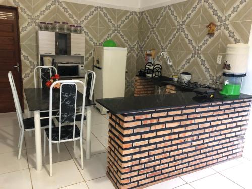 a kitchen with a counter with chairs and a refrigerator at Chalés da Boneca in Icapuí
