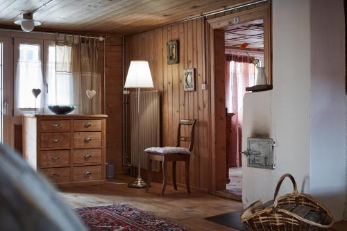 um quarto com uma cadeira, uma cómoda e um candeeiro em Nostalgie Bed & Breakfast Chrämerhus em Curaglia