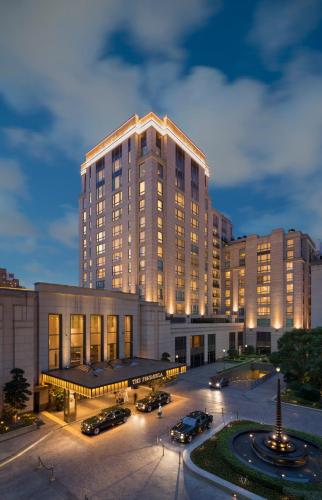 a large building with cars parked in front of it at The Peninsula Shanghai in Shanghai