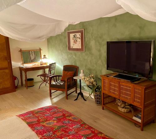 sala de estar con TV de pantalla plana y mesa en Les 3 Coeurs - Chambres chez charmants habitants, en Font