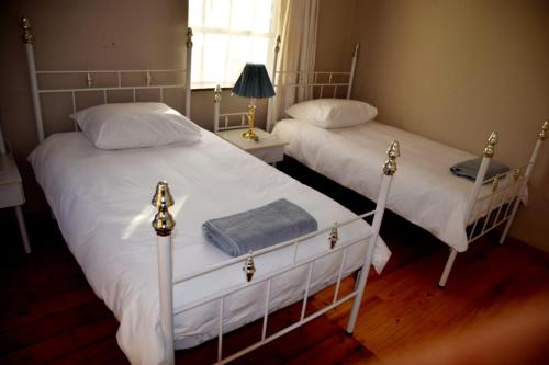 two twin beds in a bedroom with a window at Scheepers Rust Guest Farmhouse in Montagu