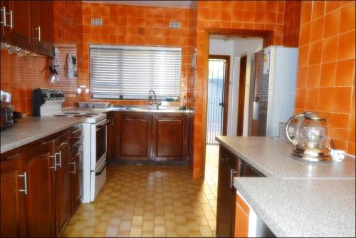 una cocina con armarios de madera y una pared de color naranja en Unit 6 Villa Marina, en Hibberdene