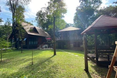 a yard with two houses and a house with a grass yard at Thanviman Forest Villa Kanjanaburi in Ban Tha Manao