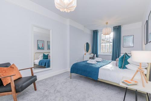 a bedroom with a blue bed and a chair at Oxfordshire Living - The Spencer Apartment - Woodstock in Woodstock