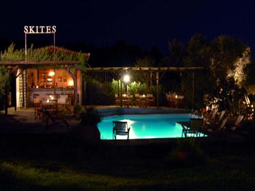 a swimming pool in front of a restaurant at night at Skites Hotel Bungalows in Ouranoupoli