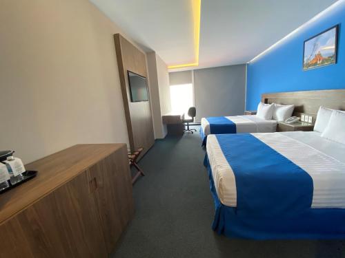 a hotel room with two beds and a couch at Wyndham Puebla Angelopolis in Puebla