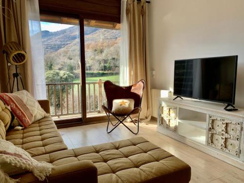 a living room with a couch and a television and a balcony at Apartament La Ruella in Sort