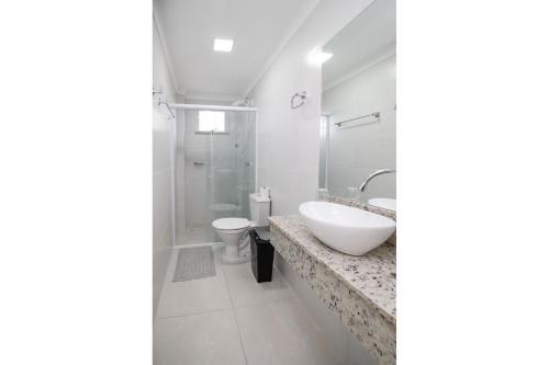Baño blanco con lavabo y aseo en Aluguel Apartamento 2 quartos s/ 1 suíte Bombas/SC, en Bombinhas