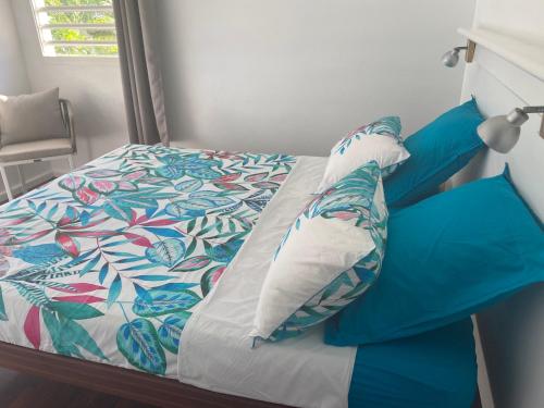 a bed with blue and white sheets and pillows at cocon caraibe in Sainte-Anne