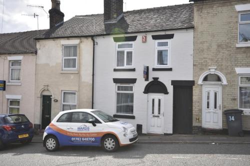 um carro estacionado em frente a uma casa branca em Townhouse @ Penkhull New Road Stoke em Stoke on Trent