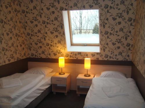 two beds in a room with a window and two lamps at Zajazd Mat in Bełk