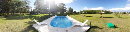 una piscina en un campo con luz solar en Cabañas La Deseada (Ranchos, Buenos Aires) en Ranchos
