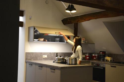 a woman in a kitchen preparing food on a counter at POSTRELAIS ARDENNES "Belle-Vue" in Burg-Reuland
