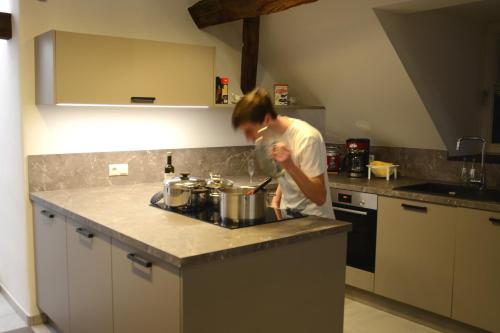 a man in a kitchen preparing food in a pot at POSTRELAIS ARDENNES "Belle-Vue" in Burg-Reuland
