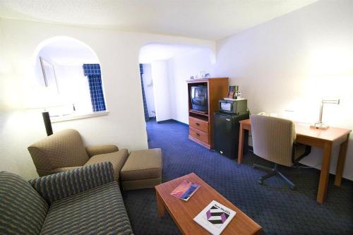 a living room with a couch and a table and a desk at Ramada by Wyndham Santa Fe in Santa Fe
