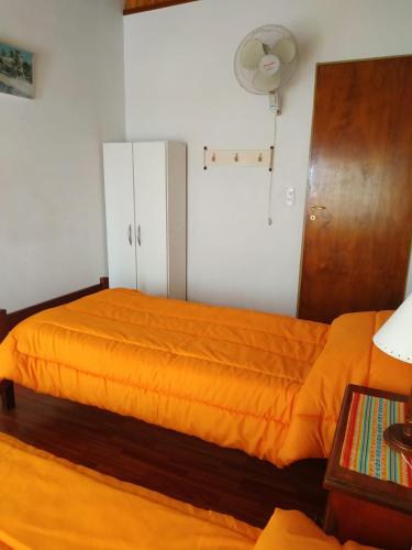 a bed with an orange blanket in a room at Departamentos Arco Iris Tandil in Tandil