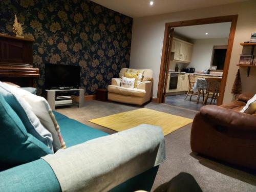 uma sala de estar com um sofá e uma televisão em Holiday House Kinveachy em Aviemore