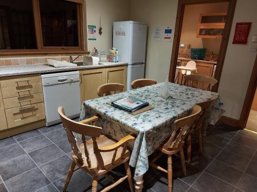 uma cozinha com uma mesa com cadeiras e um frigorífico em Holiday House Kinveachy em Aviemore