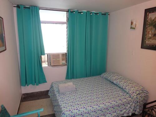 a bedroom with green curtains and a bed and a window at OUR Place 2 in San Andrés