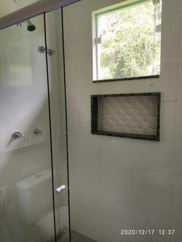 a bathroom with a shower and a toilet and a window at Pousada Cantinho da Praia in Paraty