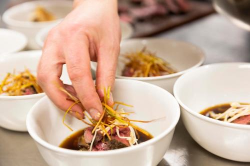 a person is adding ingredients to a bowl of food at Mt Cook Lakeside Retreat in Lake Pukaki