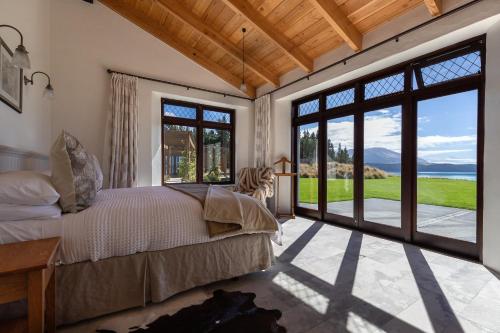 um quarto com uma cama e grandes portas de vidro deslizantes em Mt Cook Lakeside Retreat em Lake Pukaki