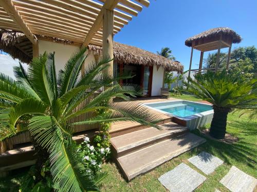 a villa with a swimming pool and a house at Tiki Pool's Bungalows in Fortim